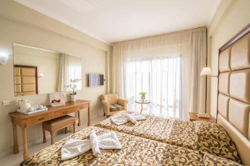 a hotel room with a bed and a desk at Tsokkos Gardens Hotel in Protaras