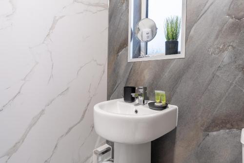 ein Badezimmer mit einem weißen Waschbecken und einem Spiegel in der Unterkunft Kirkview Apartment in Kirk of Shotts