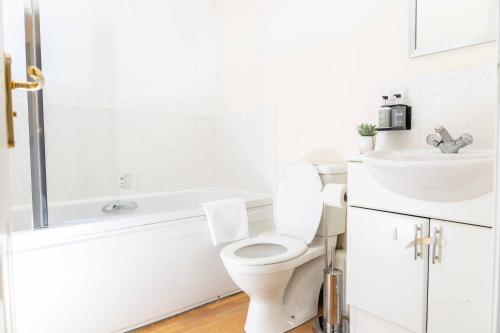 a white bathroom with a toilet and a sink at Livingston North Station Apartments in Livingston