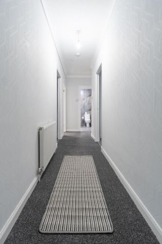 a hallway with white walls and a rug at Kirkview Apartment in Kirk of Shotts