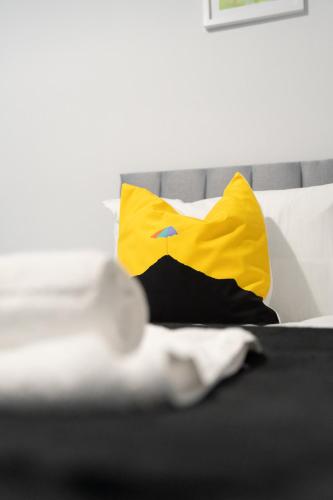 a bed with a yellow and blue pillow on it at Kirkview Apartment in Kirk of Shotts