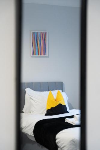 a mirror reflection of a bed with yellow and white pillows at Kirkview Apartment in Kirk of Shotts