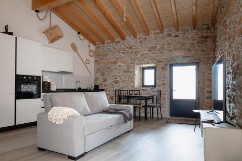 a living room with a couch and a brick wall at Casa da Broa - Recantos d'Almerinda in Alvito