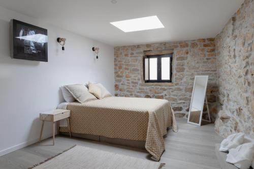 um quarto com uma cama e uma parede de pedra em Casa da Broa - Recantos d'Almerinda 