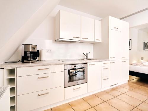a white kitchen with white cabinets and a microwave at Strandliebe in Harrislee