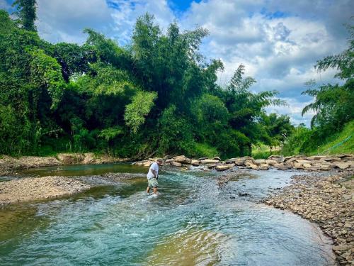 Un homme traverse un ruisseau dans une rivière dans l'établissement Amano green resort, à Ban Cha-om