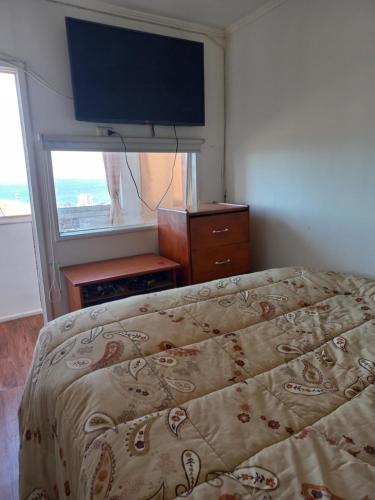 a bedroom with a bed and a flat screen tv at Apartamento por dia in Viña del Mar
