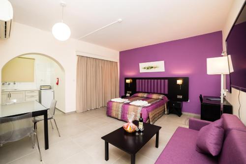 um quarto de hotel com paredes roxas e uma cama e uma mesa em Kefalos Damon Hotel Apartments em Pafos