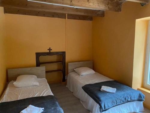 2 Betten in einem Zimmer mit einem Kreuz an der Wand in der Unterkunft Dans une Cité de Caractère. in Jugon Les Lacs