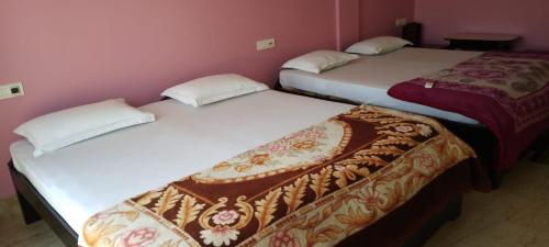three beds in a room with pink walls at Hotel Swagat in Puri