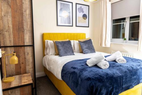 Schlafzimmer mit einem Bett mit blauer Bettwäsche und Kissen in der Unterkunft Livingston North Station Apartments in Livingston