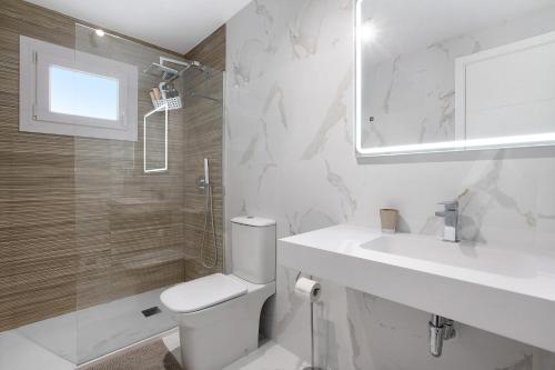 Un baño blanco con inodoro y lavabo. en Edificio Italia, en Benalmádena
