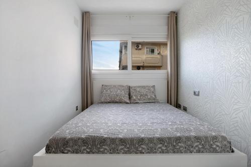 Una cama pequeña en una habitación con ventana. en Edificio Italia, en Benalmádena