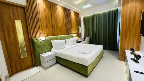 a bedroom with a bed with a green headboard at Hotel Elite Millennium - Near Huda City Centre Gurgaon in Gurgaon