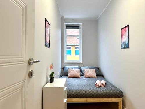 Habitación pequeña con sofá azul y 2 almohadas rosas. en MMRent Pink Room, en Gdansk