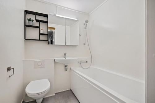 a white bathroom with a toilet and a sink at Island Getaway: Sea and Mountain Views in Ålesund