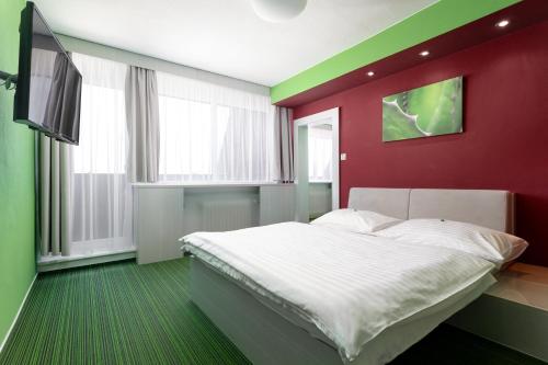 a bedroom with a red and green wall with a bed at Hotel Koruna in Opava