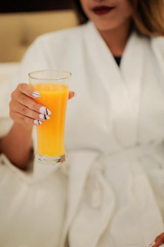 a woman is holding a glass of orange juice at Ramada by Wyndham Goa Vagator in Vagator