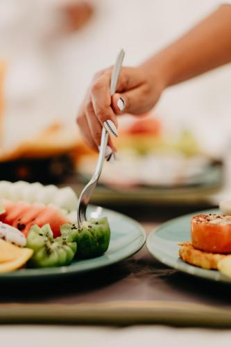 a person holding a fork in front of plates of food at Ramada by Wyndham Goa Vagator in Vagator
