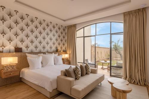 um quarto com uma cama, uma cadeira e uma janela em Ksar Char-Bagh Small Luxury Hotels em Marraquexe