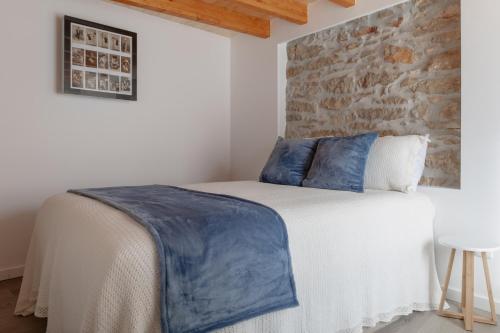1 dormitorio con 1 cama con almohadas azules y pared de piedra en Casa das Libras - Recantos d'Almerinda 