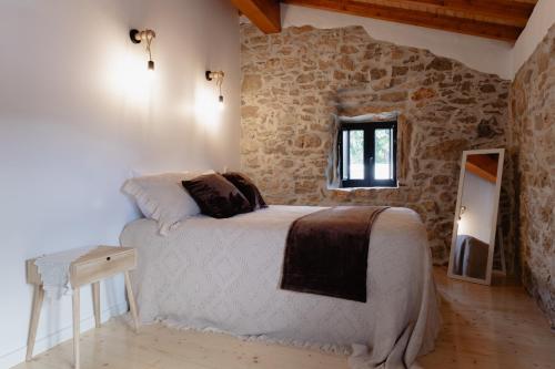 a bedroom with a bed and a stone wall at Casa da Saia Grande - Recantos d'Almerinda in Alvito