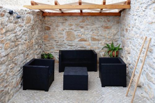 a patio with black furniture and a stone wall at Casa da Saia Grande - Recantos d'Almerinda in Alvito