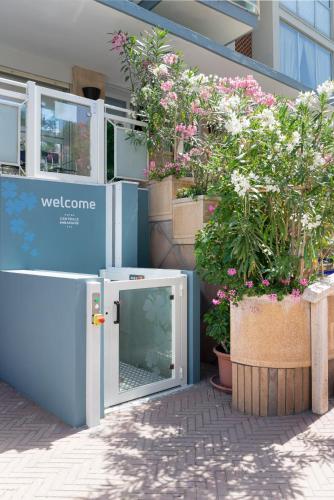 a door is open in front of a building with flowers at Hotel Centrale Miramare in Rimini