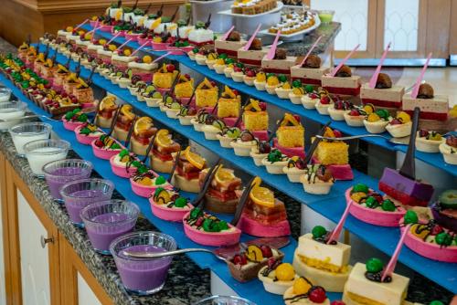 ein Buffet mit Kuchen und Desserts auf blauen Regalen in der Unterkunft Palmeras Beach Hotel Ultra All Inclusive in Konaklı