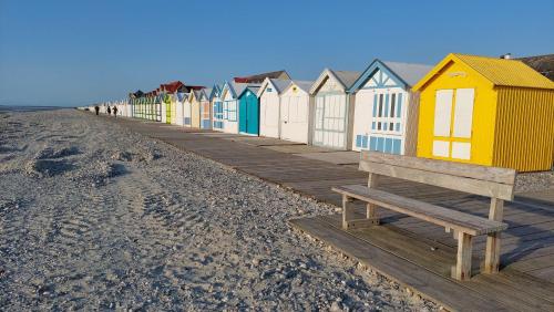 a row of colorful beach huts on the beach at gite repos et tranquillité G in Cayeux-sur-Mer