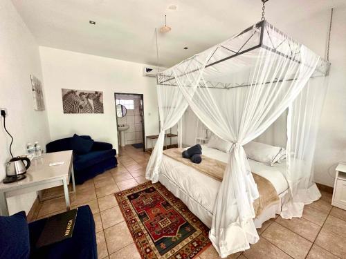 a bedroom with a bed with a canopy at Fawlty Towers Accommodation & Activities in Livingstone