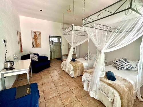 a bedroom with two beds with mosquito netting at Fawlty Towers Accommodation & Activities in Livingstone