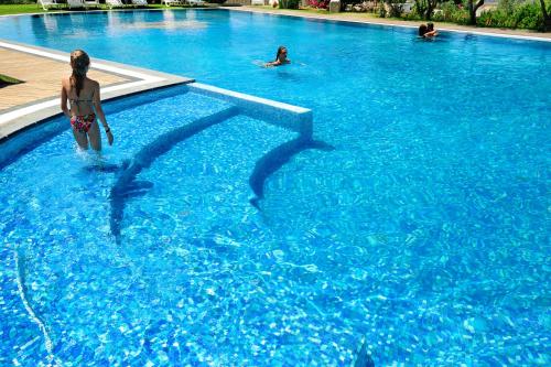 a girl in a swimming pool with dolphins in the water at Kallikoros Country Resort & Spa in Noto
