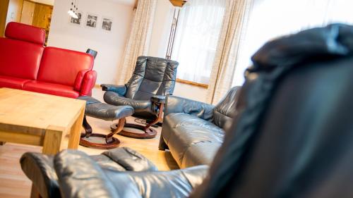 a living room with a leather couch and chairs at Haus Alpenglück in Saas-Fee