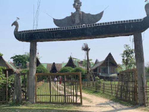 a gate with a statue of a bird and a fence at Dekasang Majuli in Majuli