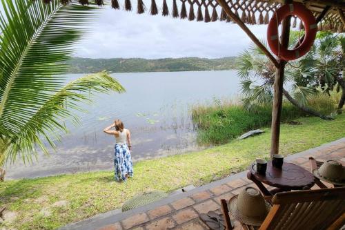 Una donna in piedi di fronte a un corpo d'acqua di Lakeside Paradise Inhambane a Ligogo