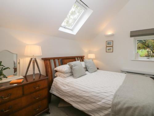 um quarto com uma cama, uma cómoda e uma janela em Harebell Cottage em Curbar