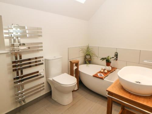 uma casa de banho com uma banheira, um WC e um lavatório. em Harebell Cottage em Curbar