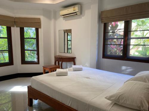 a bedroom with a large white bed with windows at Samui Green Life in Bophut 