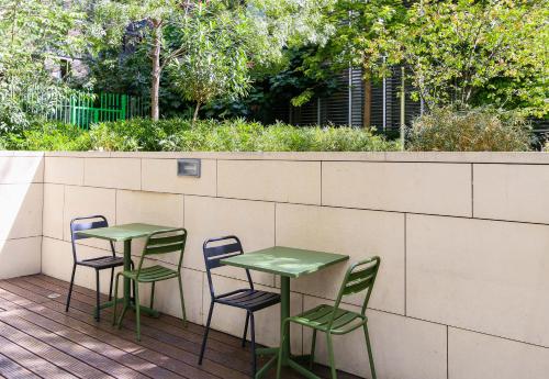 two green tables and chairs sitting on a deck at B&B HOTEL Marseille Euromed in Marseille