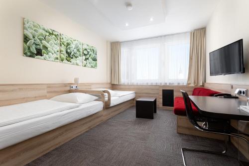 a hotel room with two beds and a flat screen tv at Hotel Koruna in Opava