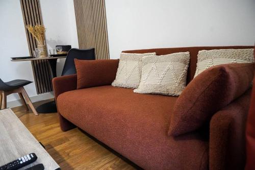 - un canapé brun avec des oreillers dans le salon dans l'établissement Le Raspail • Pour un séjour confortable • Fibre, à Châteauroux