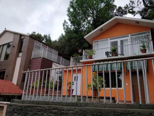 Casa de color naranja con balcón con macetas en Essence of Nature, Ranikhet, en Rānīkhet