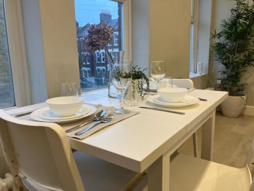 a white table with plates and glasses on it at Brilliant 2 Bed Apartment - 2 The Southwell in London