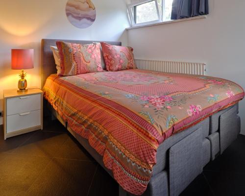 een slaapkamer met een bed, een lamp en een raam bij Bungalow AMNIS in Lanaken