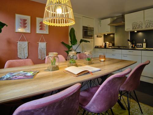 a dining room table with a book and purple chairs at Bungalow AMNIS in Lanaken