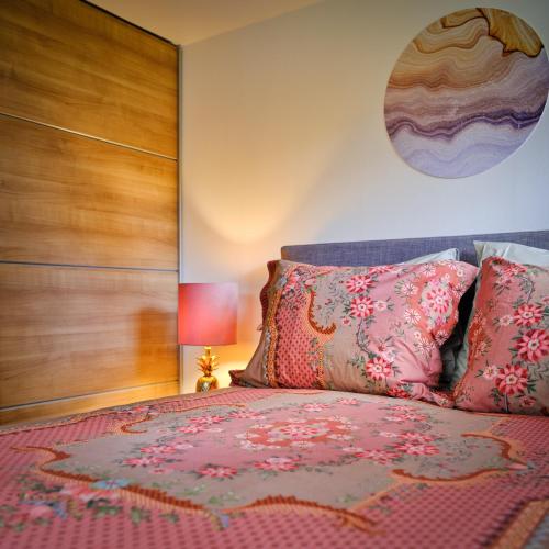 a bedroom with a large bed with pink pillows at Bungalow AMNIS by Sonnevijver Residences in Lanaken