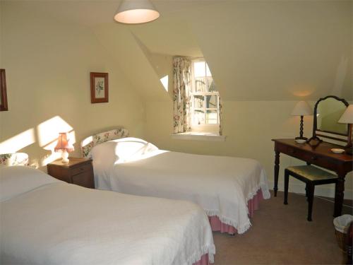 a bedroom with two beds and a desk and a window at 2 Bed in Kinlocheil CA138 in Fassfern