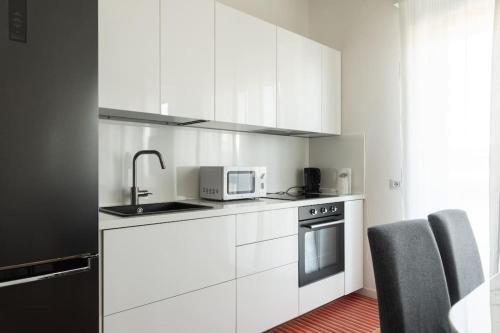 a kitchen with white cabinets and a sink and a microwave at Youhosty - Soderini 25 in Milan