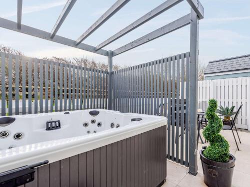 a hot tub on a patio with a fence at 2 Bed in Westward Ho 77289 in Northam